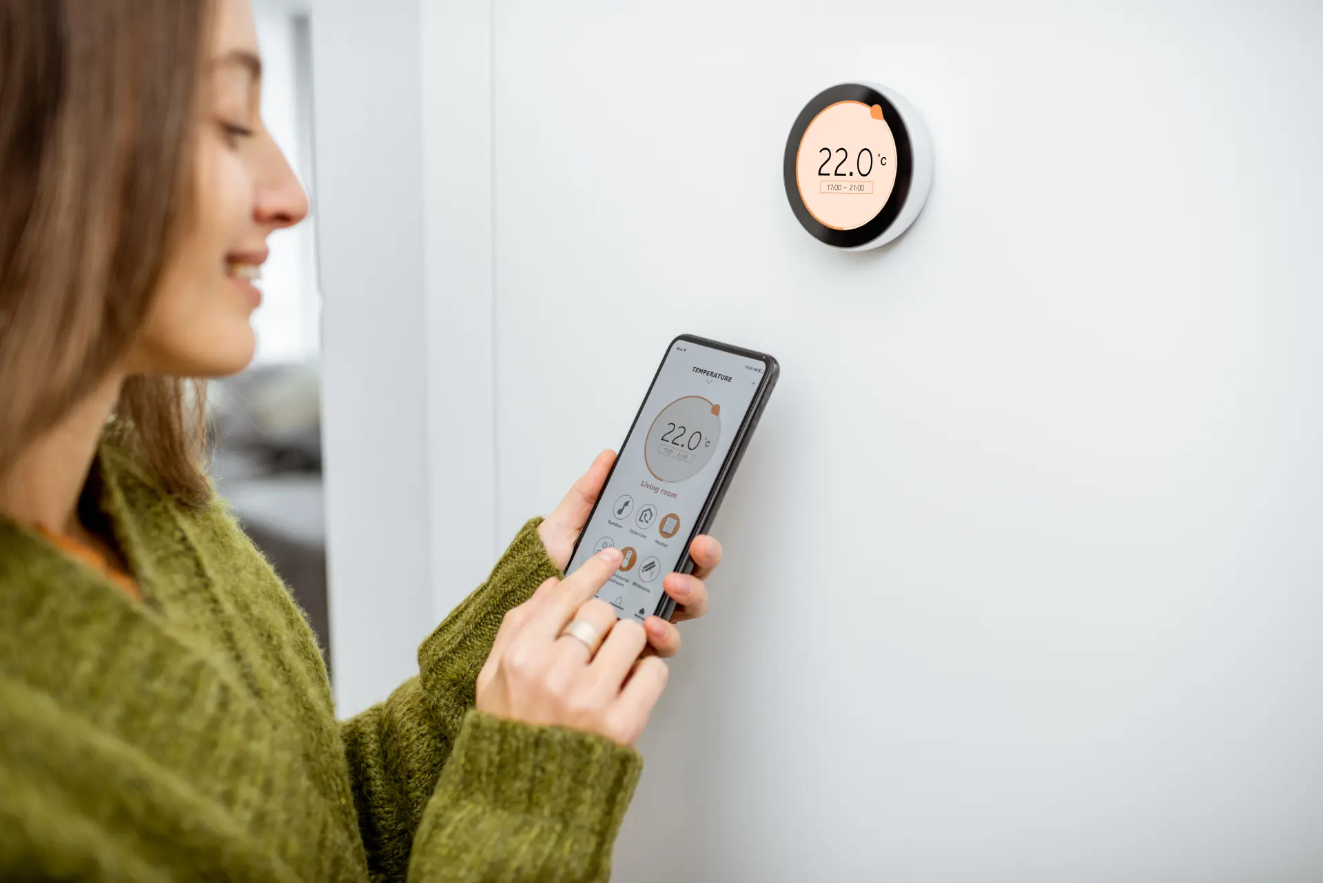 Žena nastavuje smart termostat pomocou mobilnej aplikácie, teplota nastavená na 22 °C.