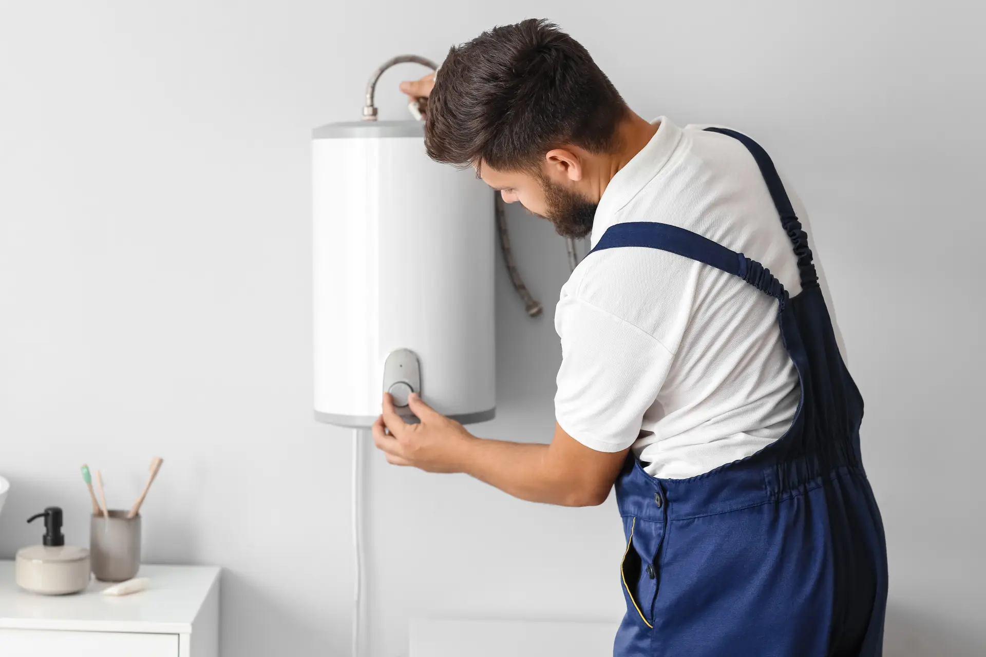 Inštalatér kontroluje správnu funkciu nového elektrického bojlera namontovaného na stenu kúpeľne.