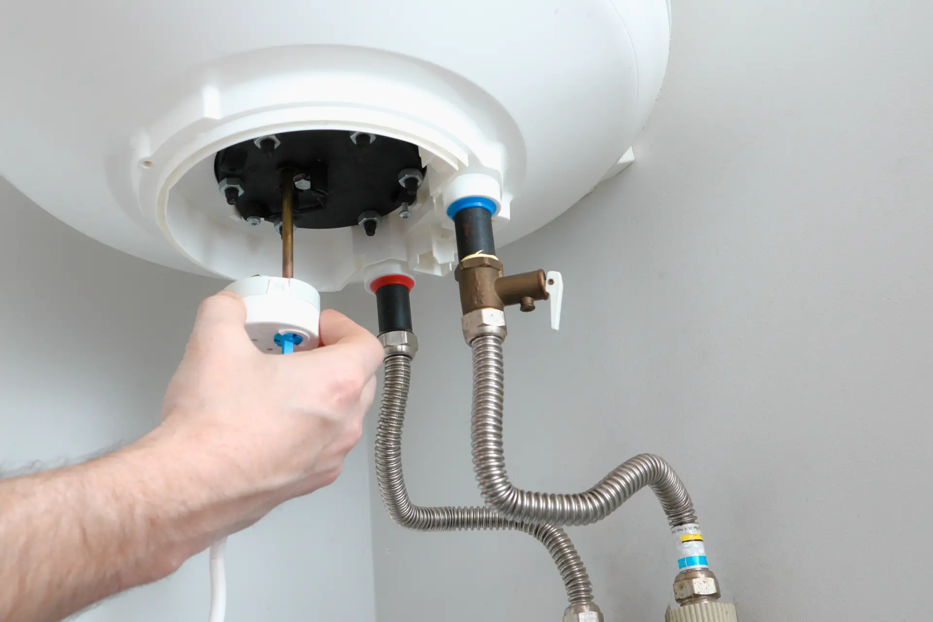 Technik vykonáva údržbu elektrického bojlera a kontroluje pripojenie výhrevného telesa.