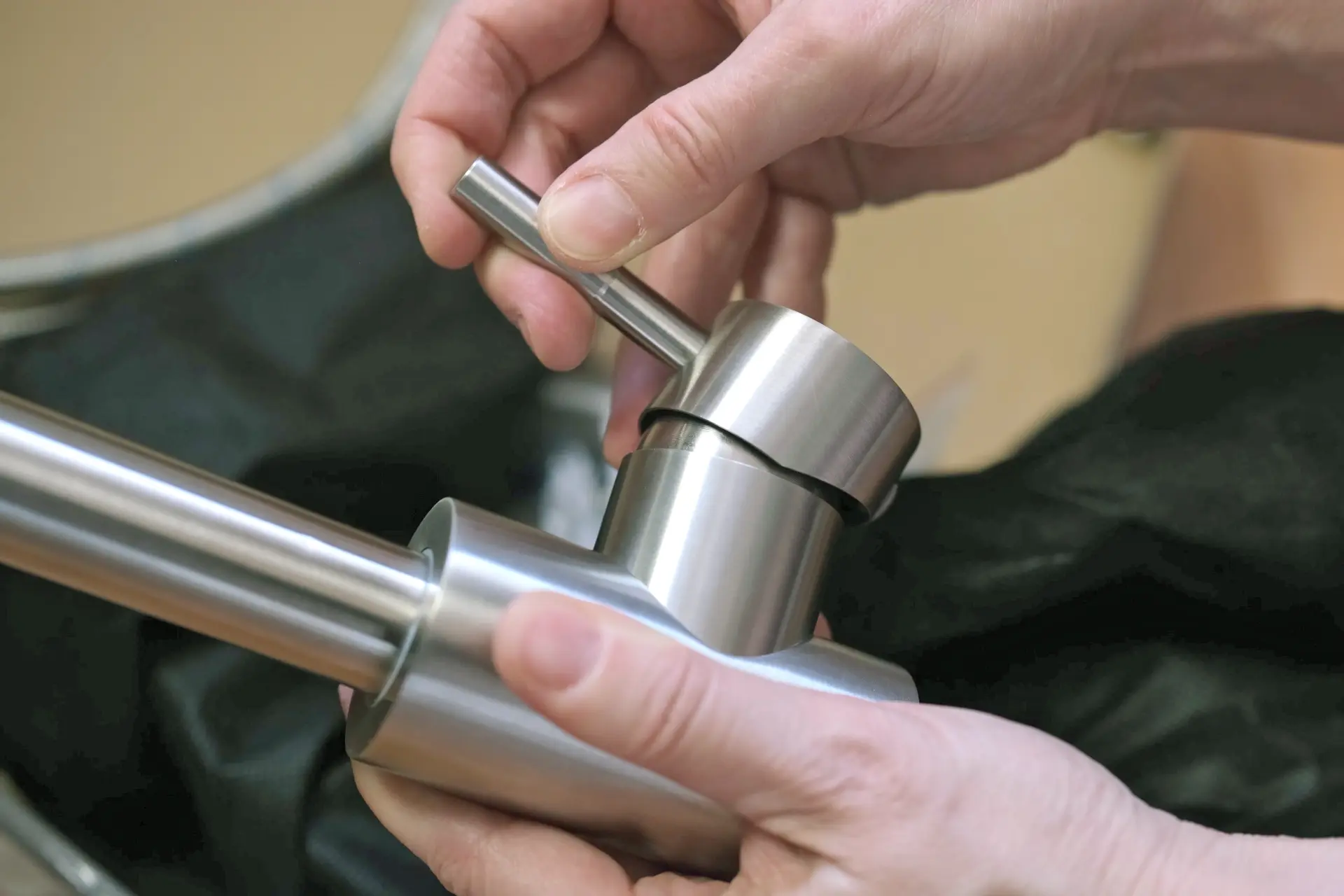 Montáž kuchyňské baterie, kde ruce drží kovovou pákovou armaturu.