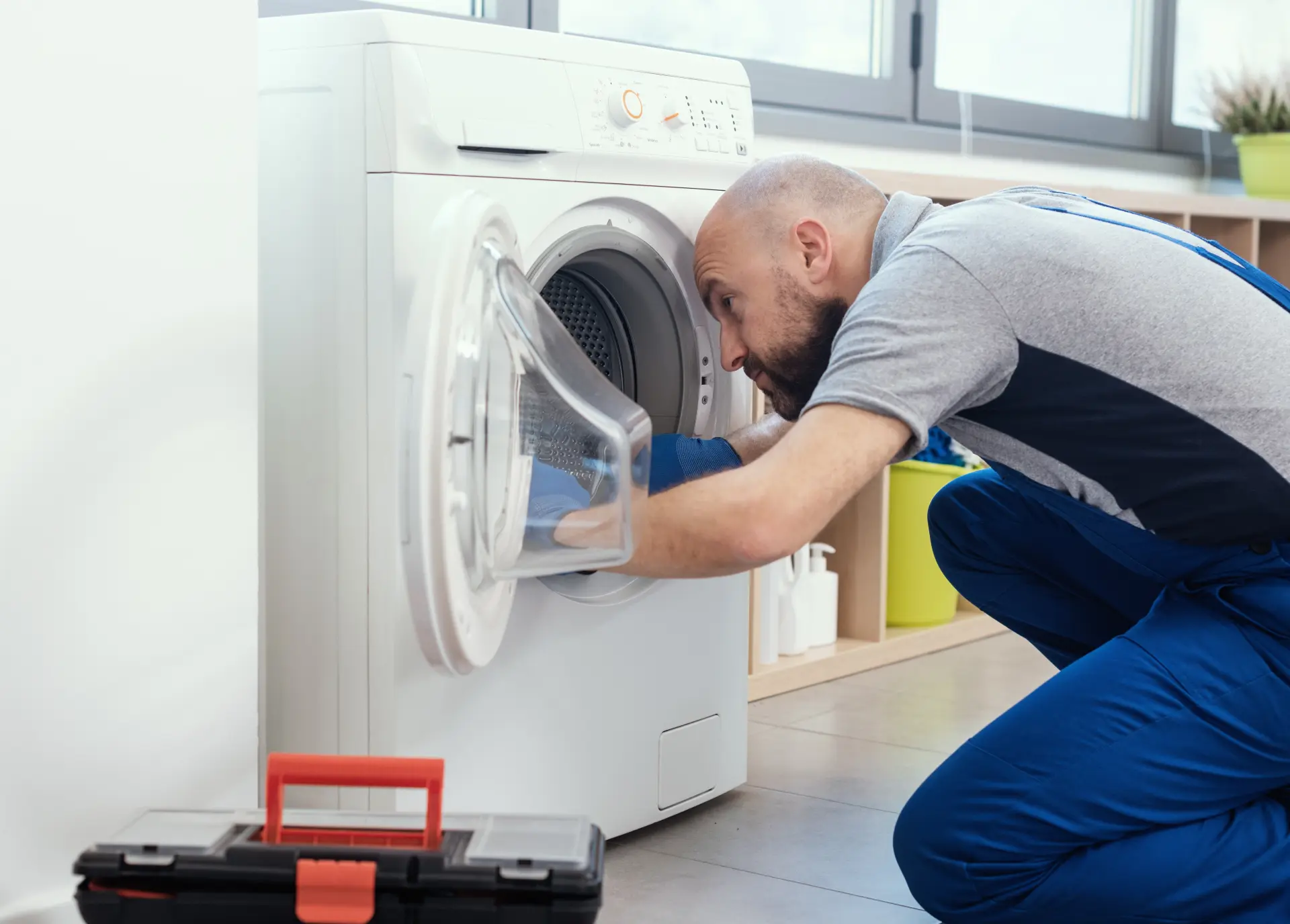 Technik opravuje bubon práčky a kontroluje jej vnútorné súčiastky.