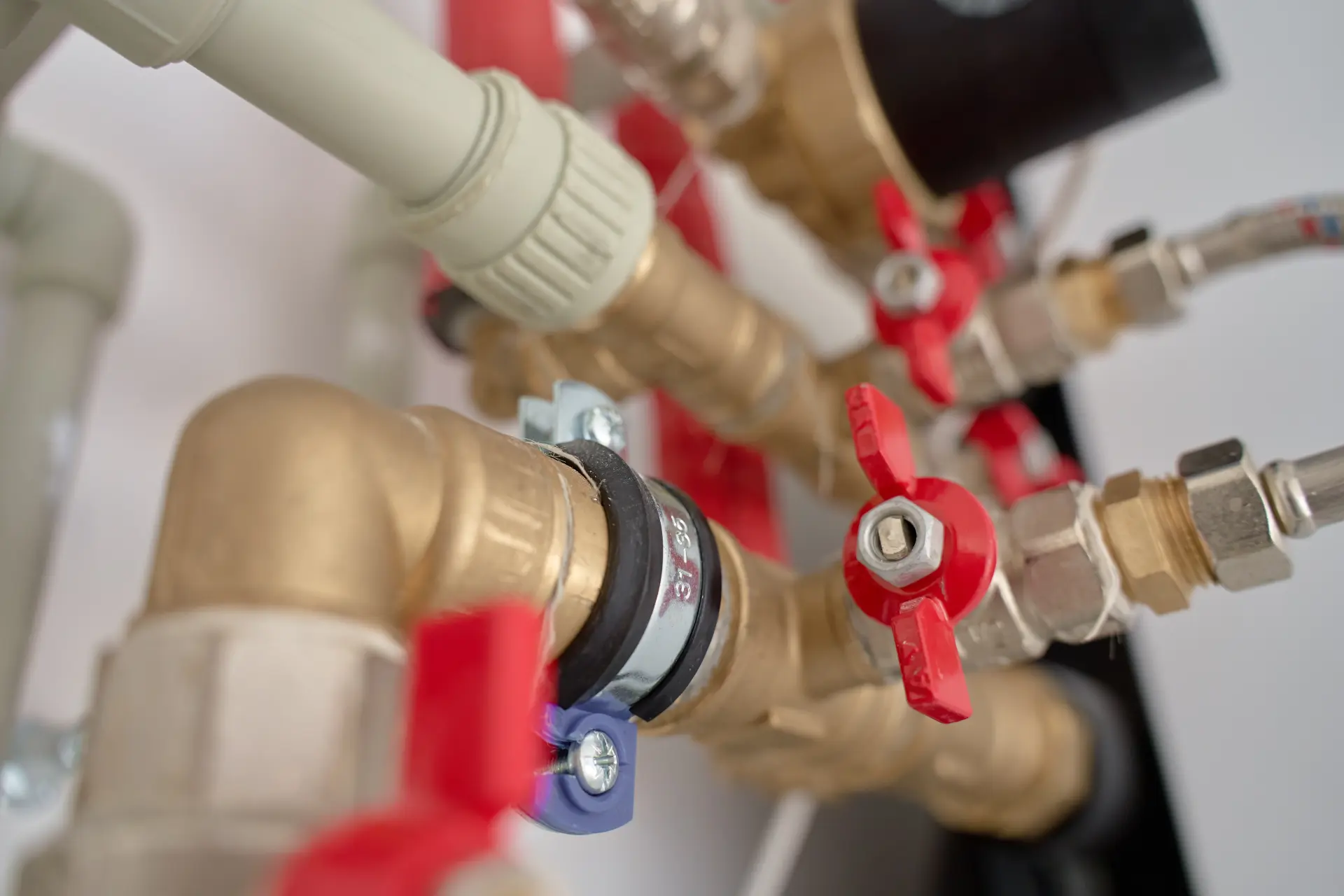 etail mosadzných rozvodov vody s uzatváracími ventilmi a plastovým potrubím v technickej inštalácii.