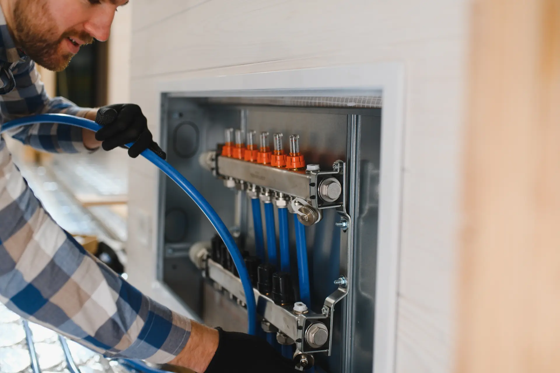 Inštalatér pripája hadice do rozdeľovača podlahového kúrenia.