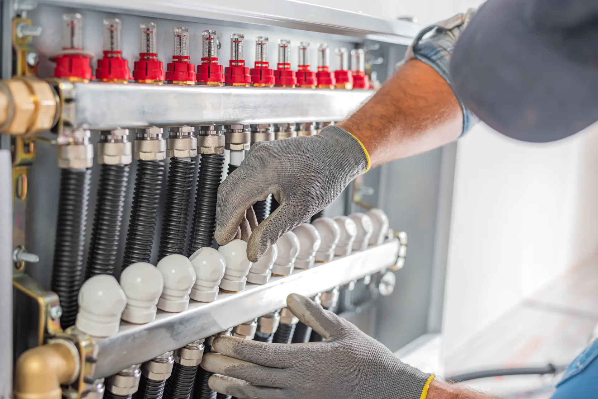 Technik vykonáva servis rozdeľovača podlahového kúrenia s náradím.