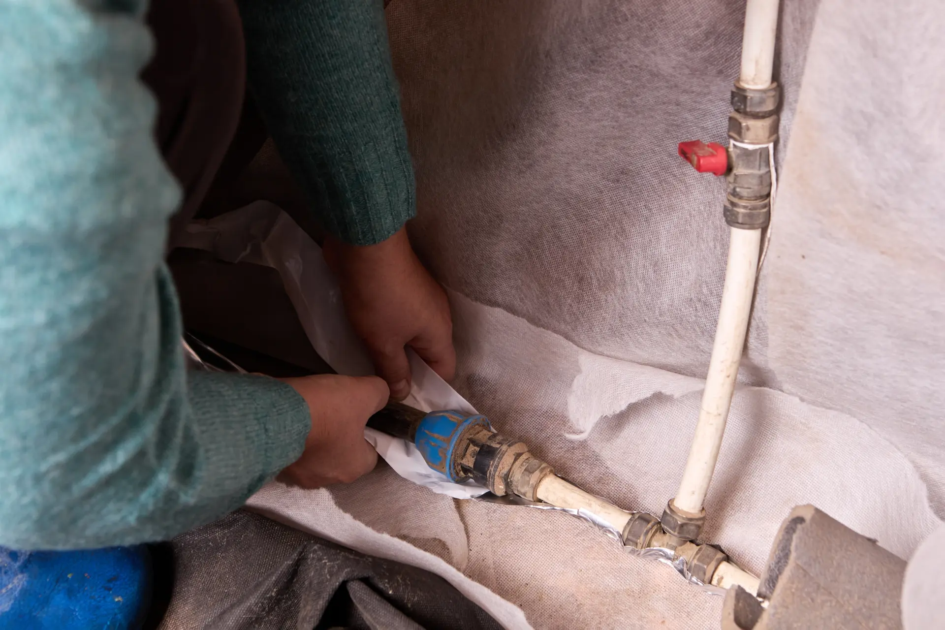 Dočasná oprava prasknutého vodovodného potrubia pomocou fólie a tesnenia.