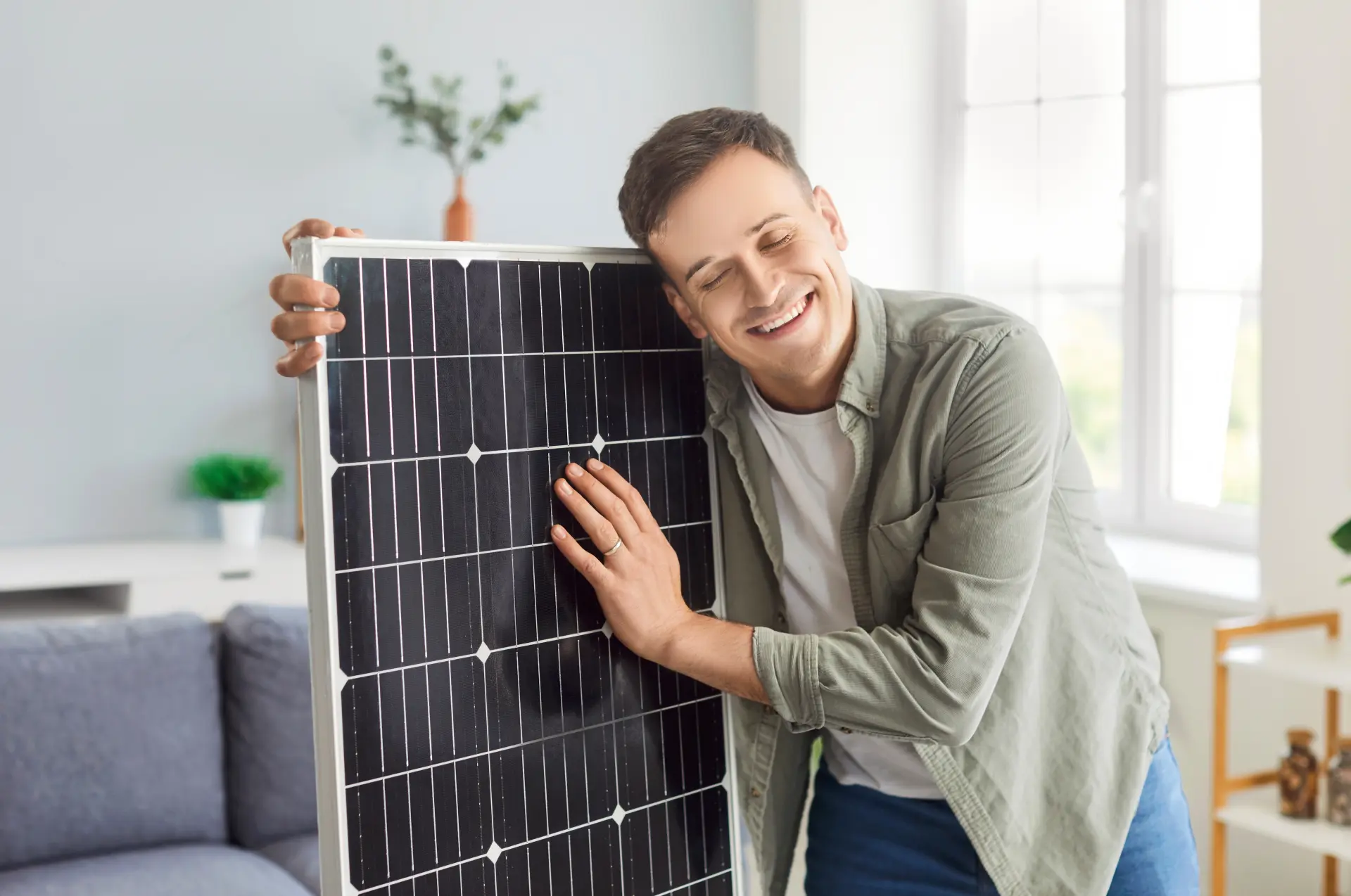Muž drží a ukazuje solárny panel v interiéri ako riešenie obnoviteľnej energie.