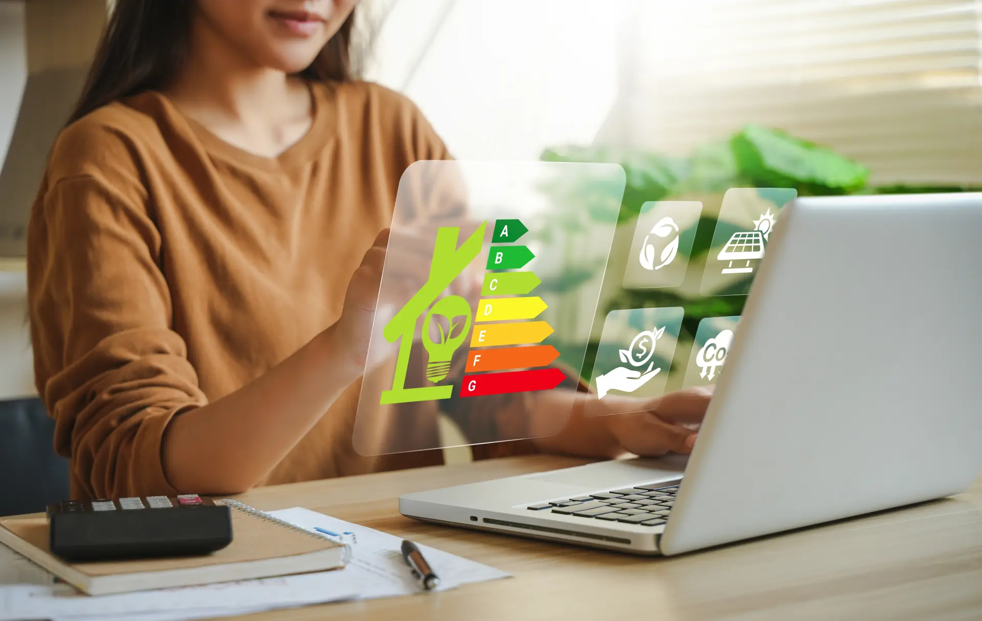 Žena pracuje na notebooku a kontroluje energetický štítok domu s hodnotením spotreby energie.