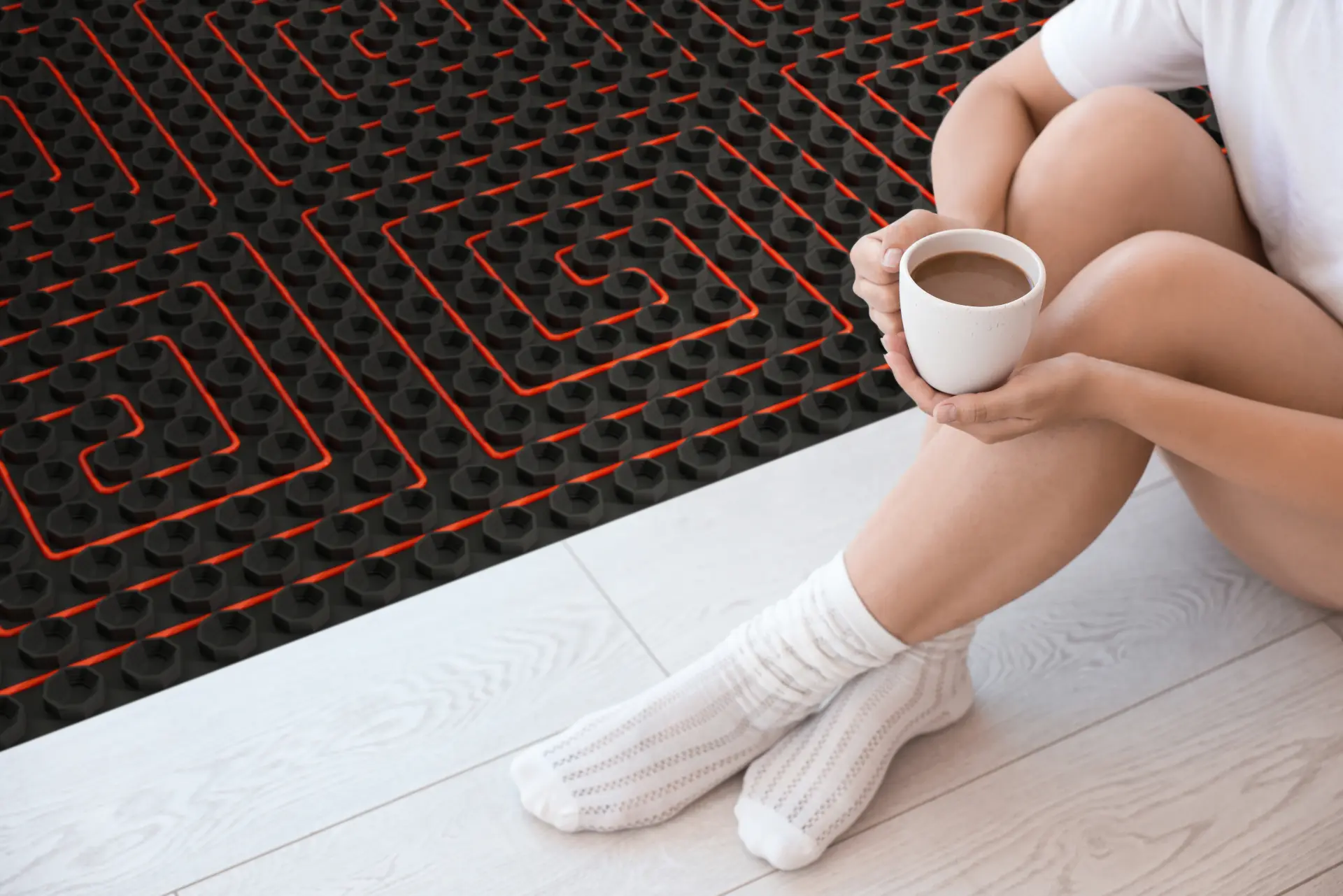 Pohodlie podlahového kúrenia v domácnosti pri oddychu s horúcim nápojom na teplej podlahe.