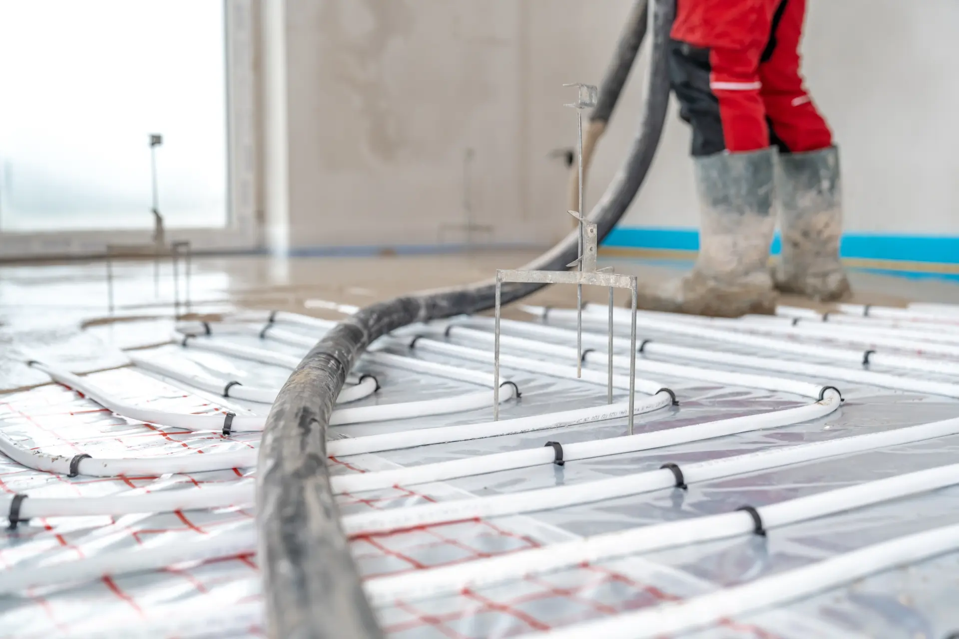 Liatie poteru na podlahové kúrenie s rozvodmi hadíc počas stavebných prác v interiéri.