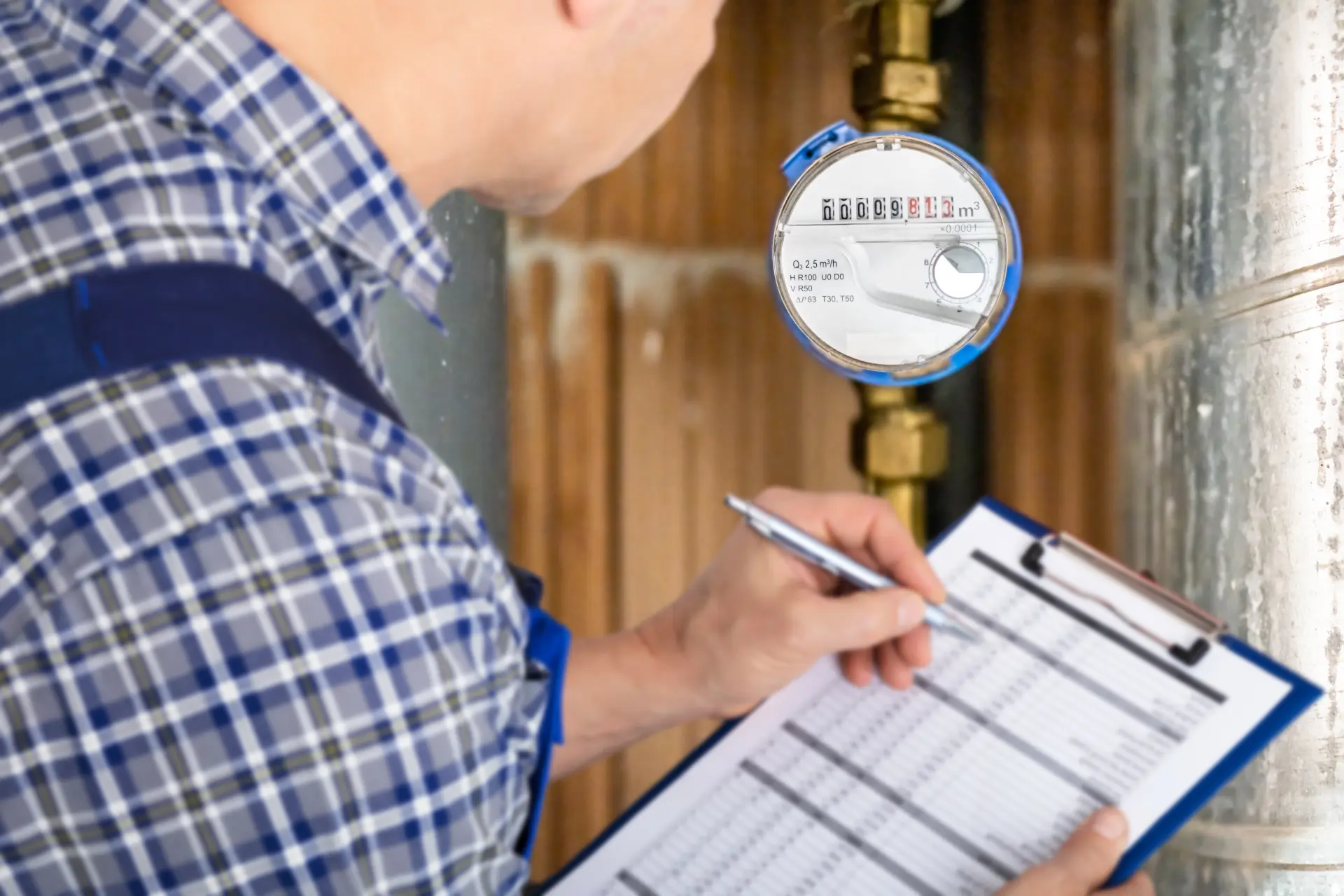 Technik zapisuje stav vodomeru pri kontrole spotreby vody v bytovom alebo rodinnom dome.