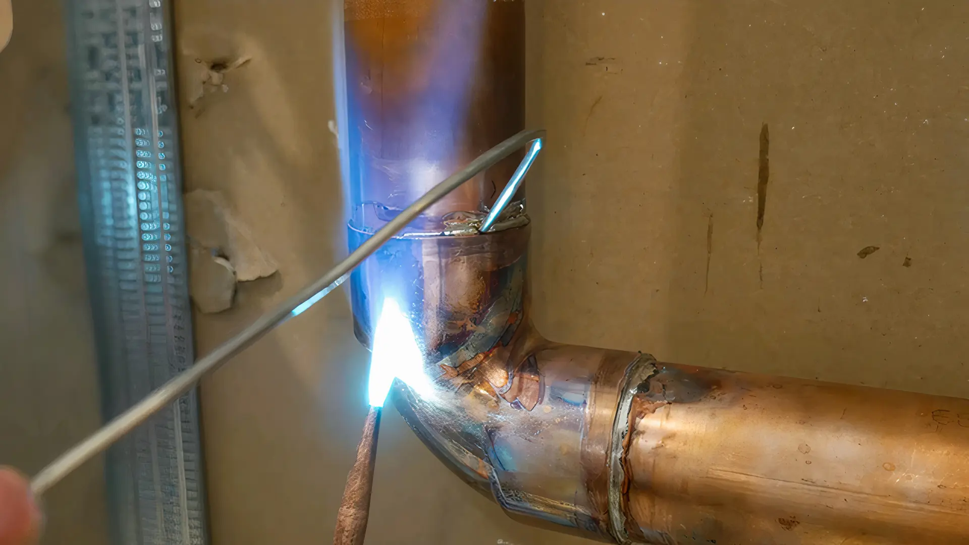 Spájkovanie medených rúr pomocou plynového horáka pri oprave vodovodného potrubia.