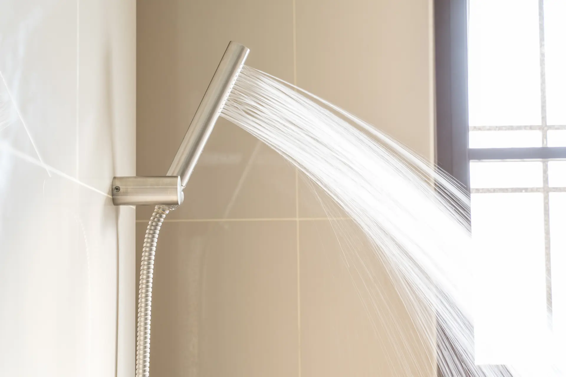 Moderná sprchová hlavica so silným prúdom vody v kúpeľni pri každodennom sprchovaní.