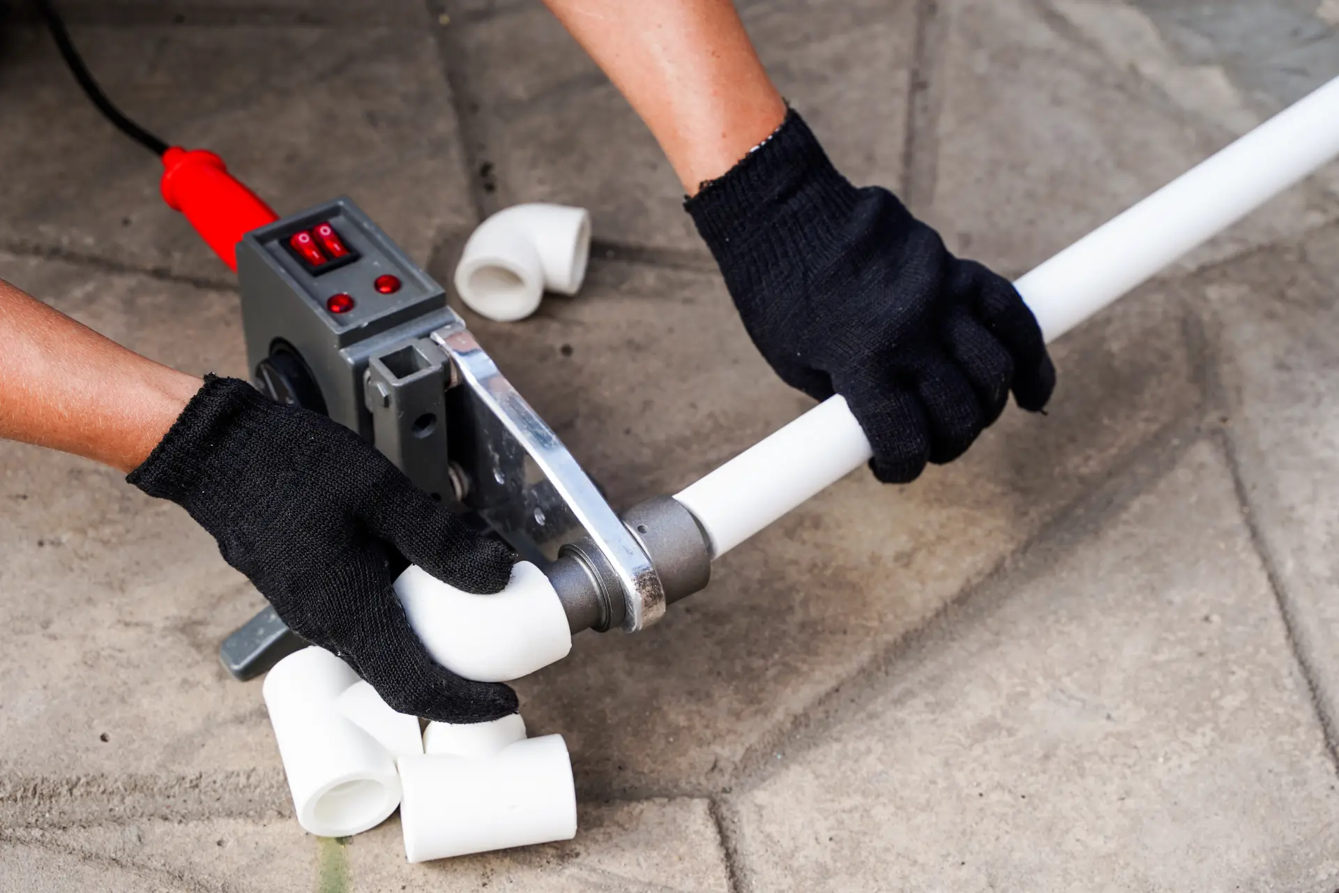 Spájanie plastových rúr pomocou zváracieho nástroja pri inštalácii vodovodného systému.