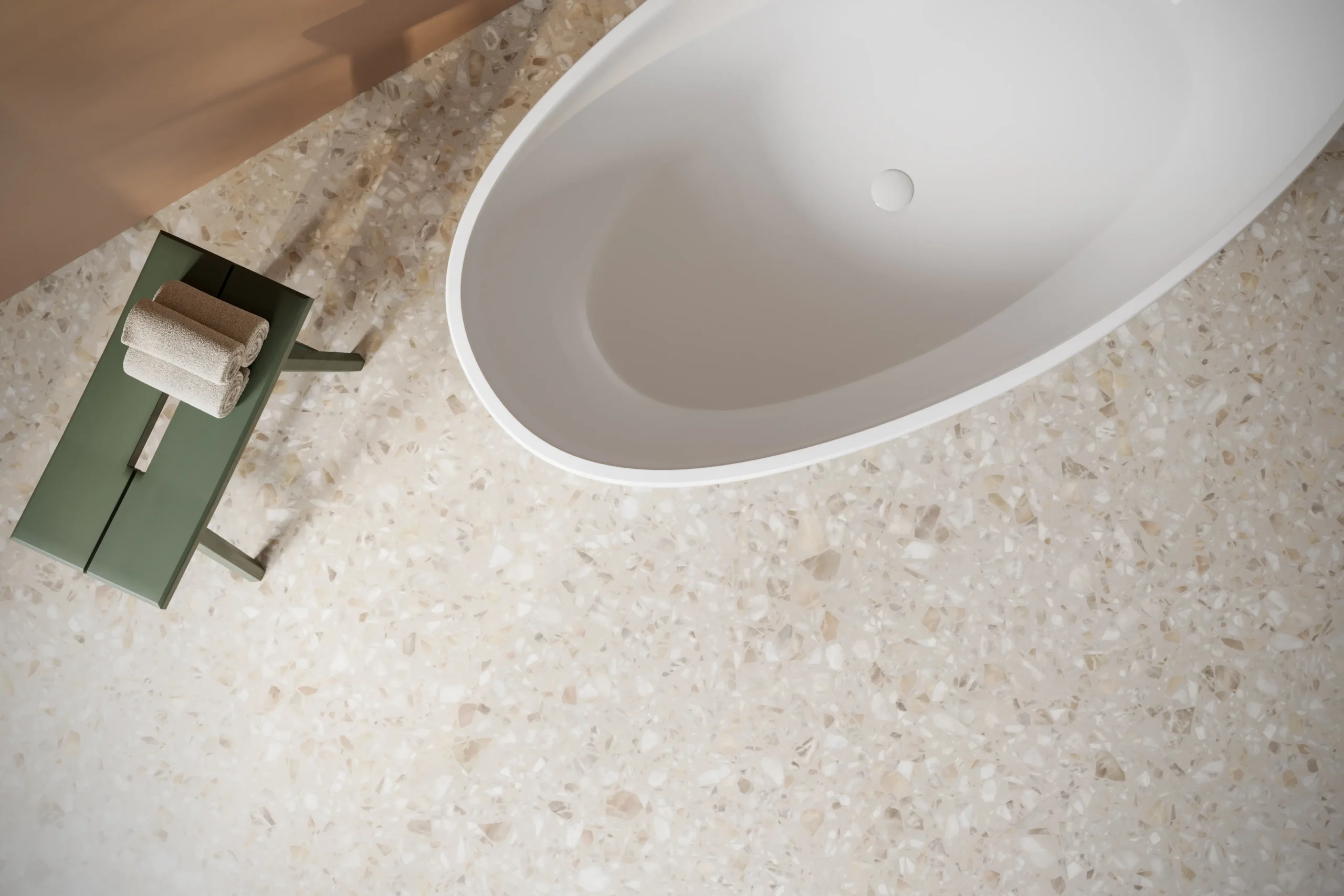 Oválna voľne stojaca vaňa umiestnená na terrazzo podlahe v modernej kúpeľni s elegantným vzhľadom.