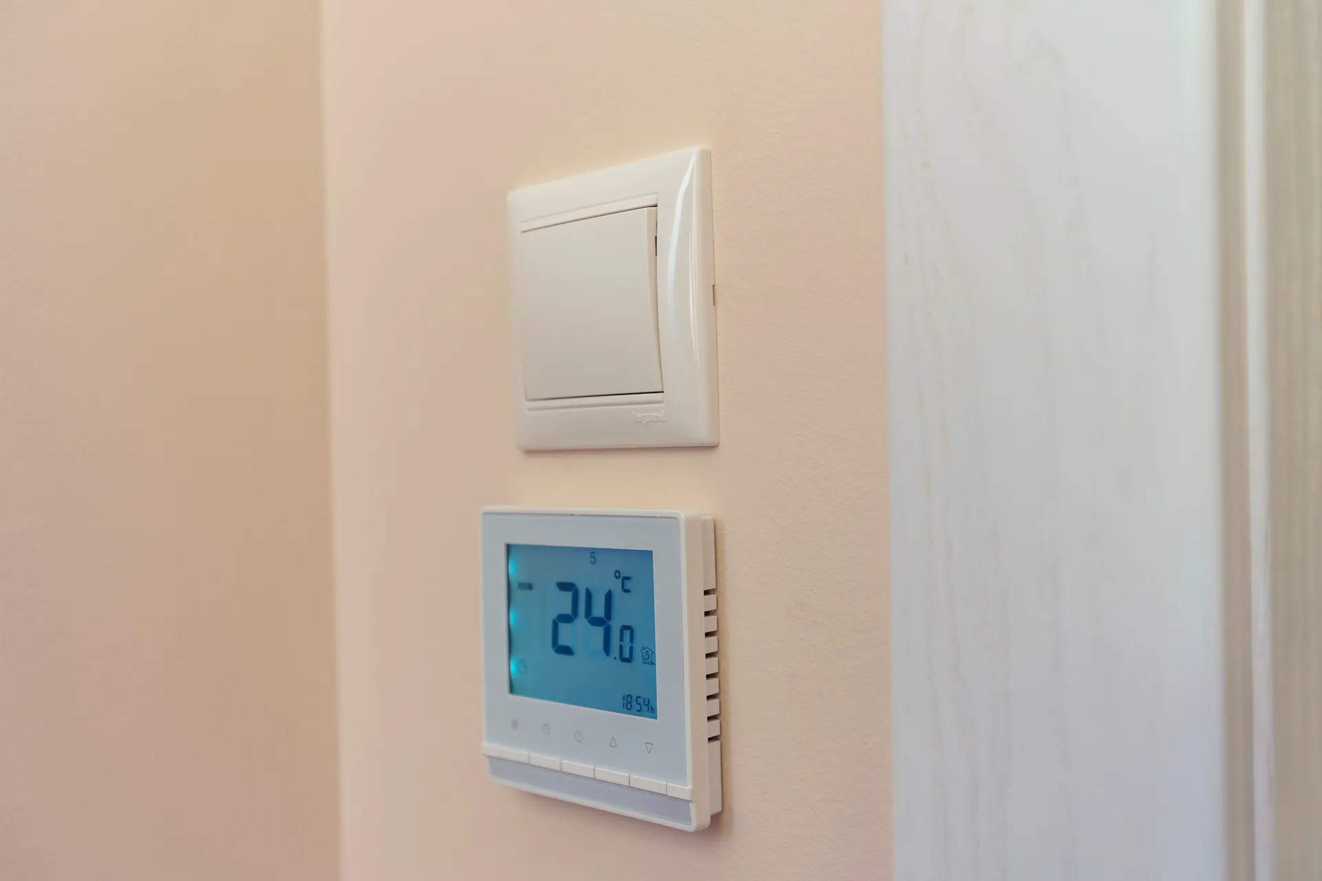 Digitálny izbový termostat na stene zobrazujúci teplotu 24 °C na reguláciu vykurovania miestnosti